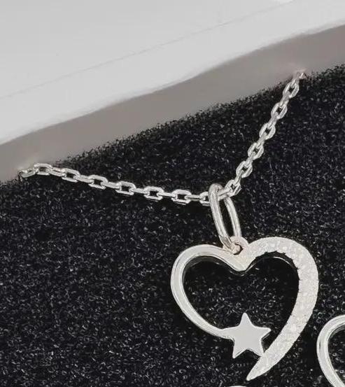 Silver heart-shaped pendant with a star cutout on a black textured surface