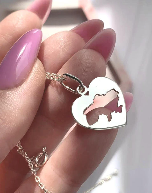 Silver heart-shaped pendant necklace featuring a precise cutout of Ukraine, symbolizing love and connection to the country. Set against a pink and white marbled background, the piece combines elegance with personal significance. Ideal for those who cherish their heritage or support Ukraine, this minimalist design offers both style and meaning.