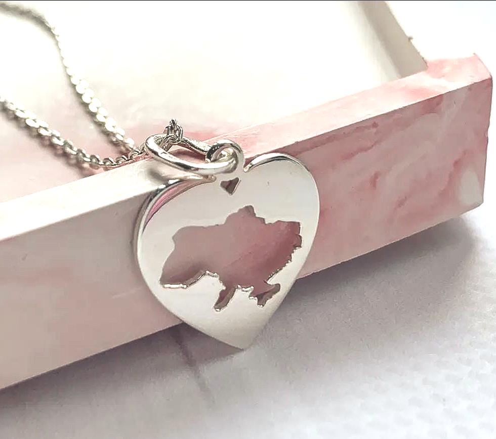 Silver heart-shaped pendant with a bear silhouette on a pink and white background