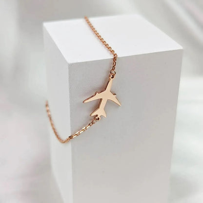 Rose gold airplane necklace on a white cube