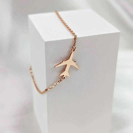Rose gold airplane necklace on a white cube