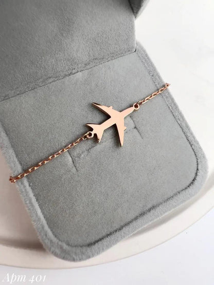 Rose gold airplane-shaped bracelet on a gray jewelry pouch