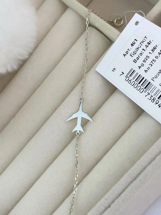 Silver airplane-shaped necklace on a beige surface with a price tag.