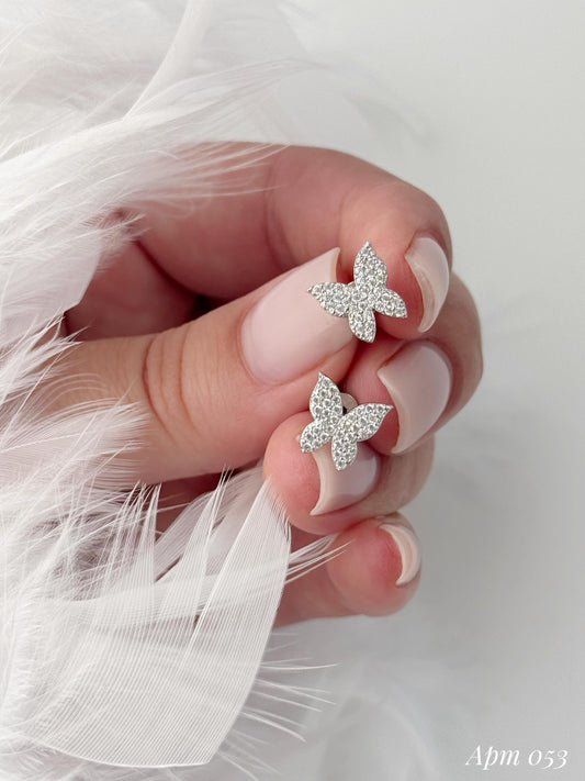 Butterfly-shaped earrings on a hand with white feathered background